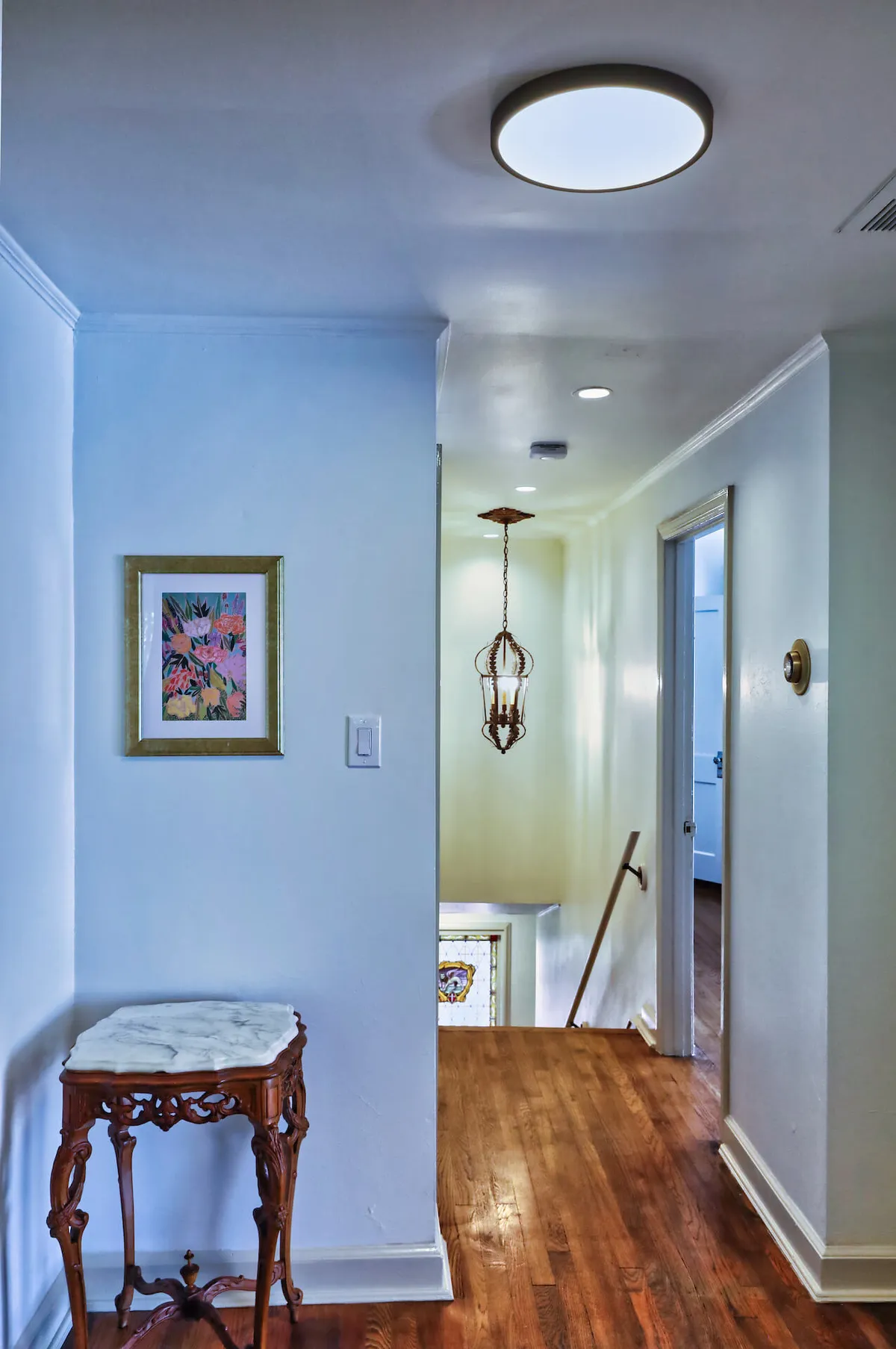 An elegant entryway or sitting area highlighted by framed artwork, an ornate chandelier, and a decorative table. The space feels inviting and refined, suitable for greeting guests or enjoying quiet moments.